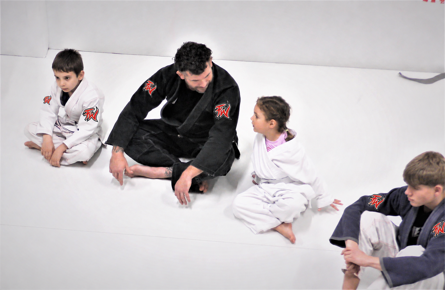 An instructor supporting children during a martial arts class